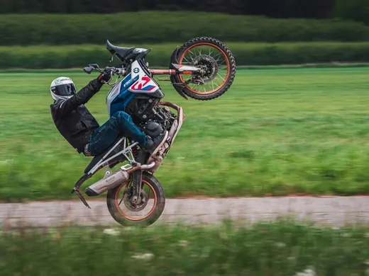 Jezdec na zadním kole na BMW F 850 GS na silnici mezi poli