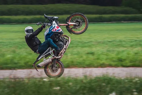 Jezdec na zadním kole na BMW F 850 GS na silnici mezi poli