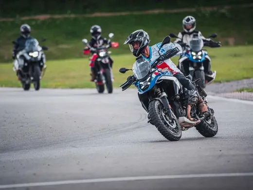 Skupina jezdců na motorkách BMW v zatáčce okruhu, v čele instruktor