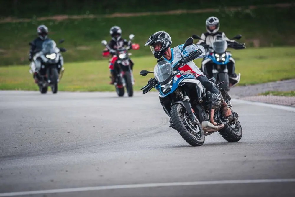 Skupina jezdců na motorkách BMW v zatáčce závodního okruhu
