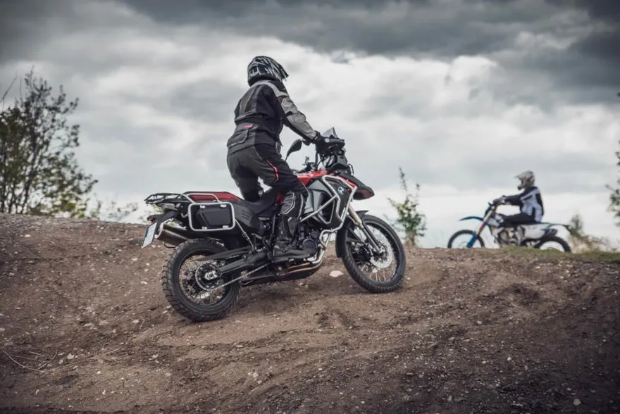 Jezdec na BMW F 800 GS ve stoje na hliněném valu pod bouřkovou oblohou