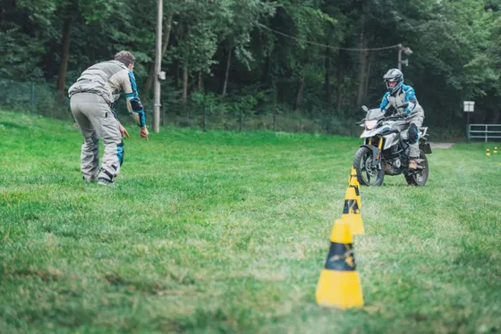 Lektor navádí studenta na lehkém enduru BMW mezi kužely v terénu